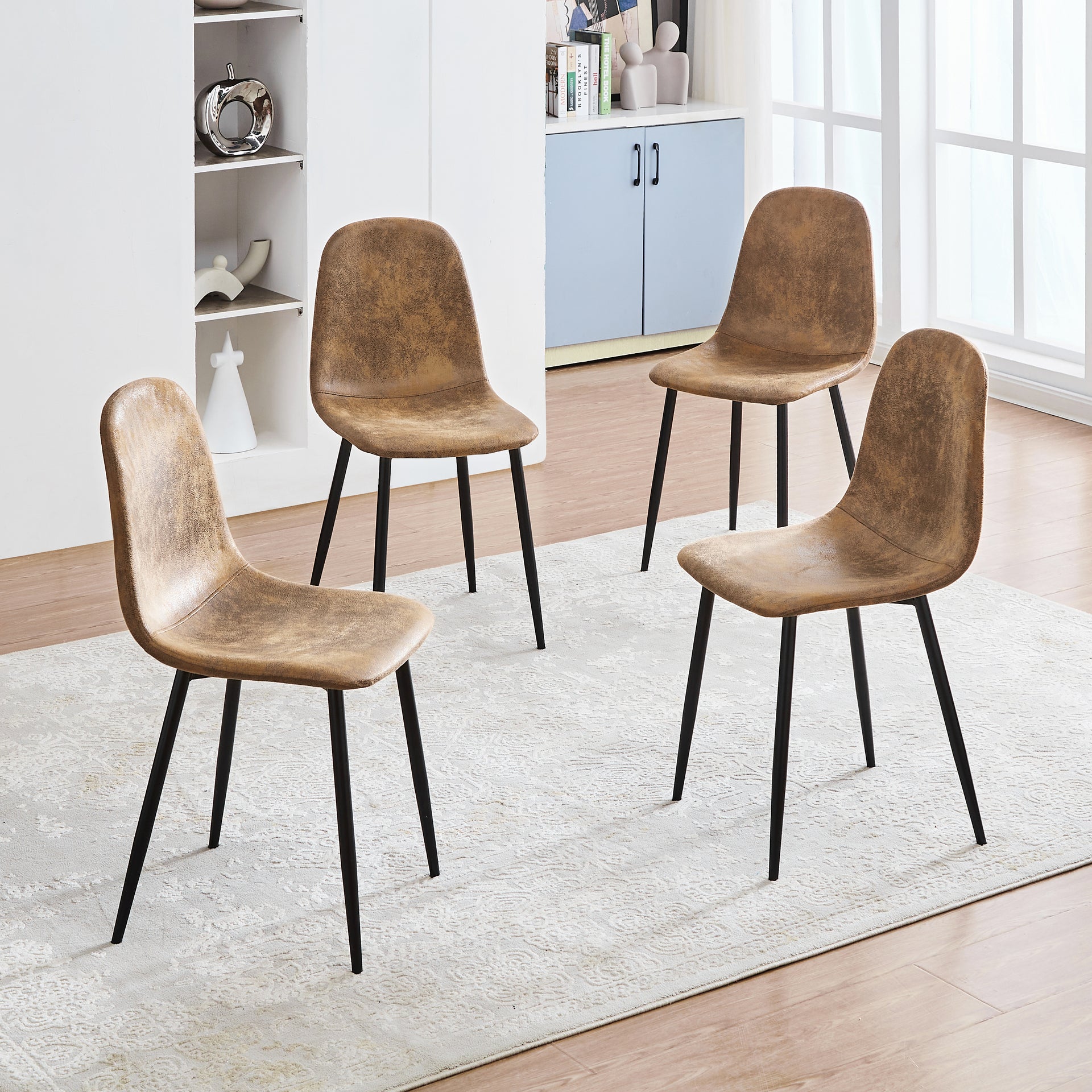 Ensemble de quatre chaises de salle à manger en suédine beige avec pieds en métal noir. La coque incurvée soutient le dossier et la structure fine permet un gain de place dans les cuisines, les salles à manger et les appartements.
