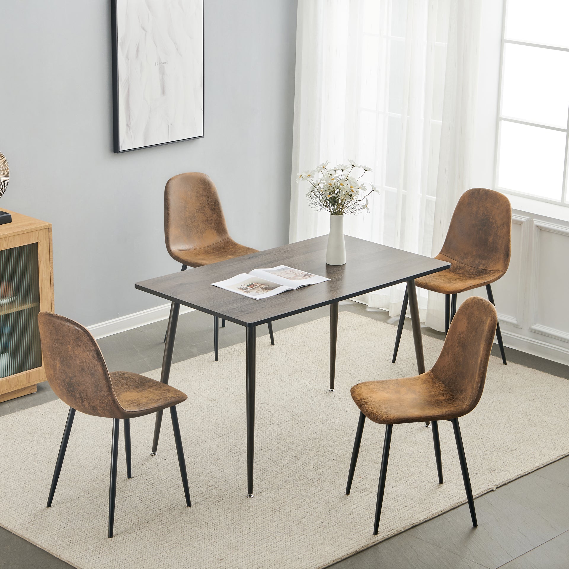 Ensemble de quatre chaises de salle à manger en suédine beige avec pieds en métal noir. La coque incurvée soutient le dossier et la structure fine permet un gain de place dans les cuisines, les salles à manger et les appartements.
