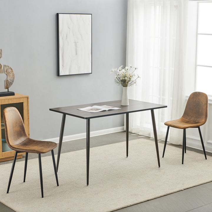 Set of four tan faux suede dining chairs with black metal legs. Curved shell supports the back and a slim frame saves space for kitchens, dining rooms, and apartments.